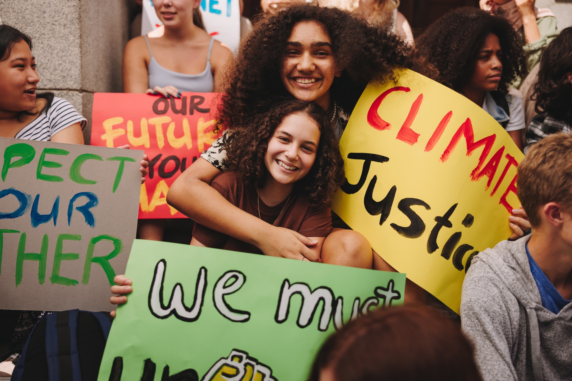 Smiling teenage girls sitting with a group of climate activists