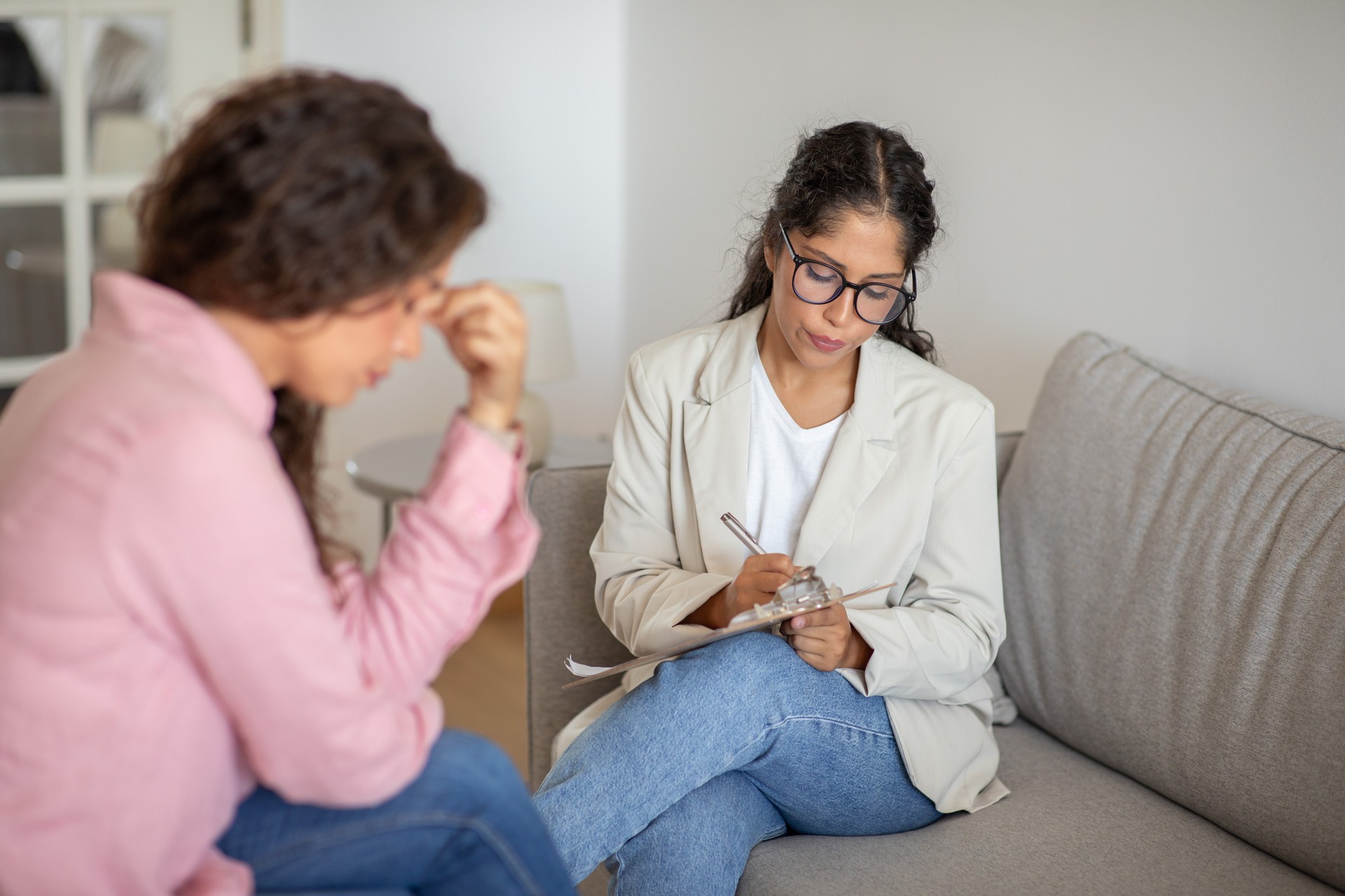 Woman in White Blazer Taking Notes During Therapy Session